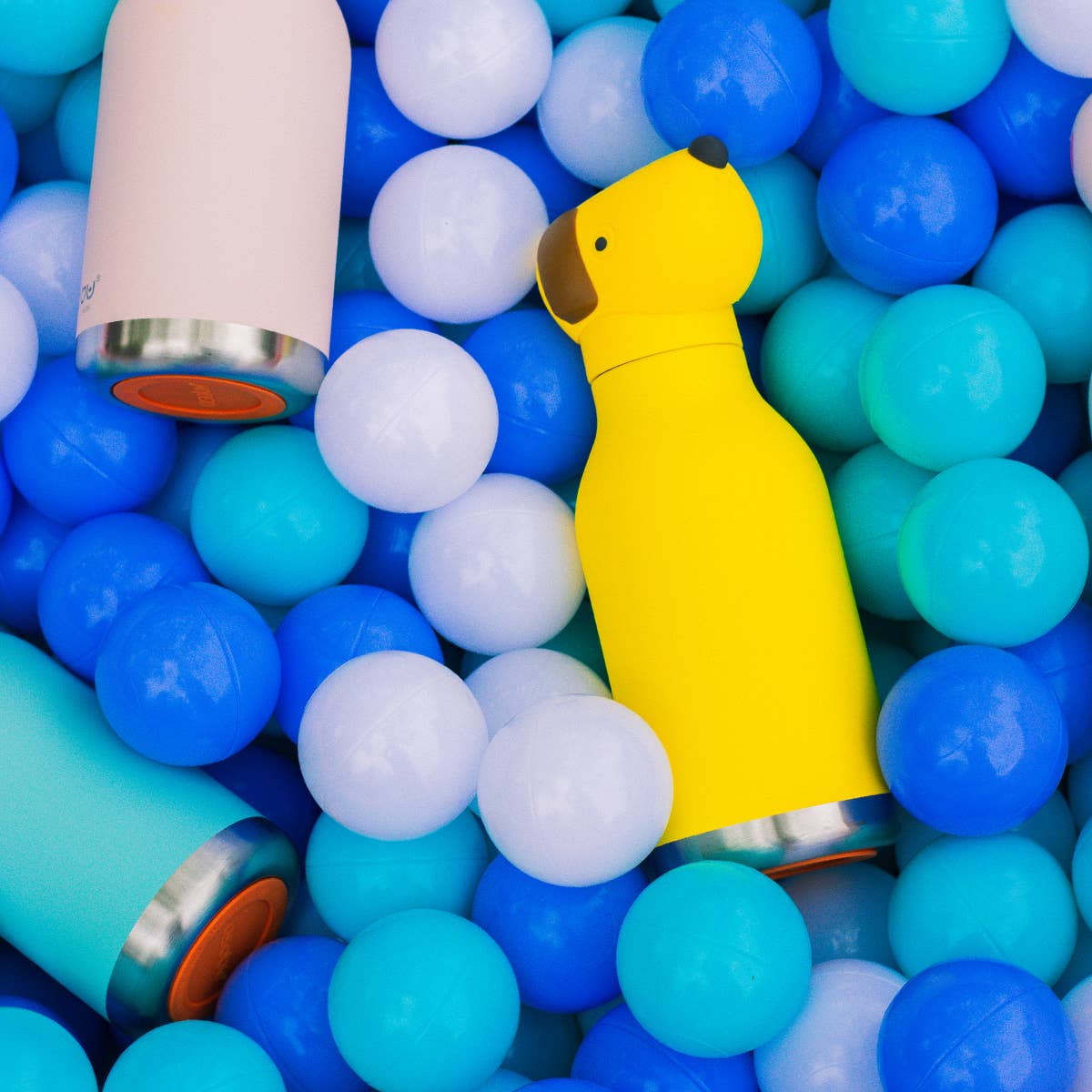 Yellow dog-shaped water bottle among colorful plastic balls