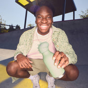 Person holding a green bottle at a skate park