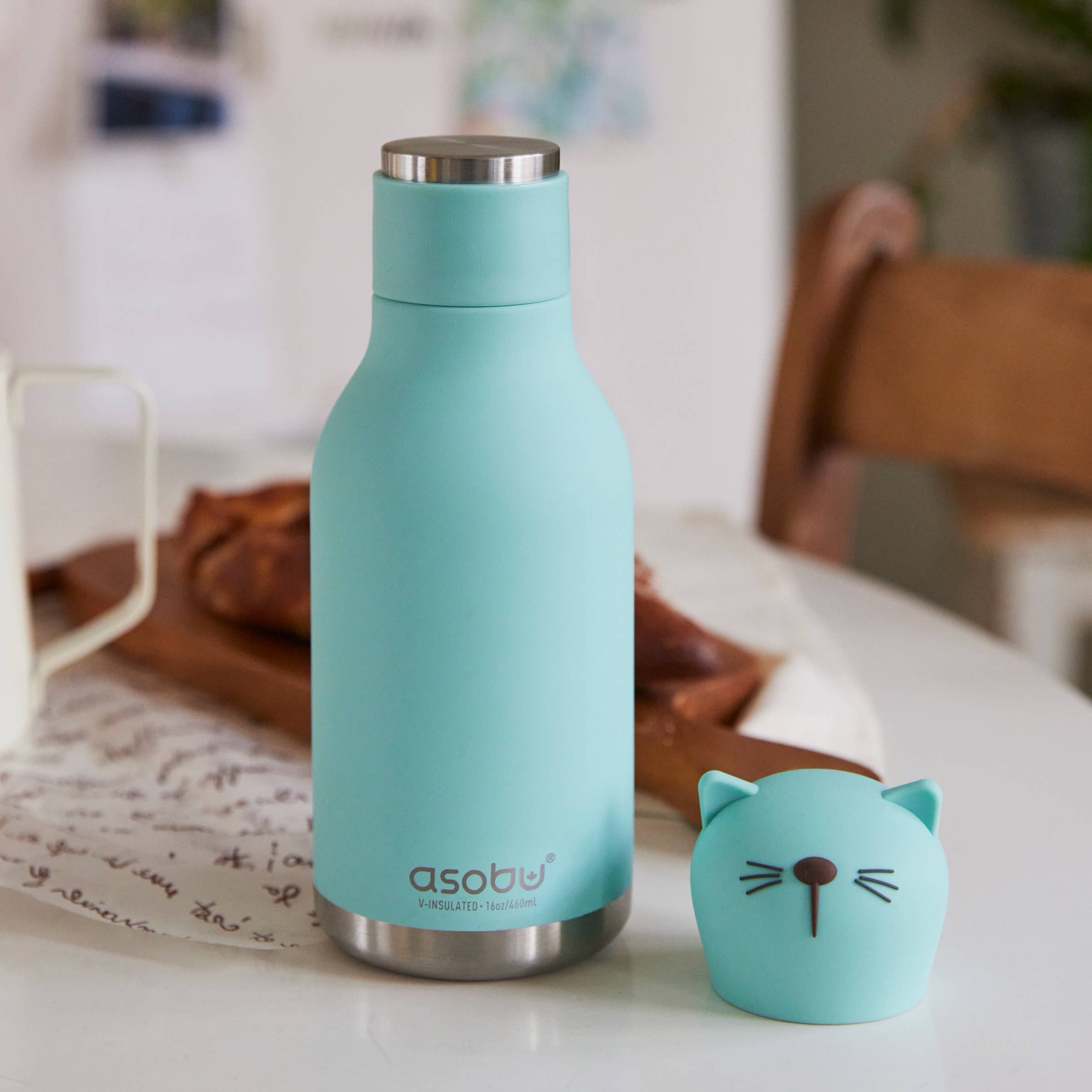 Turquoise water bottle with cat-shaped lid on a table