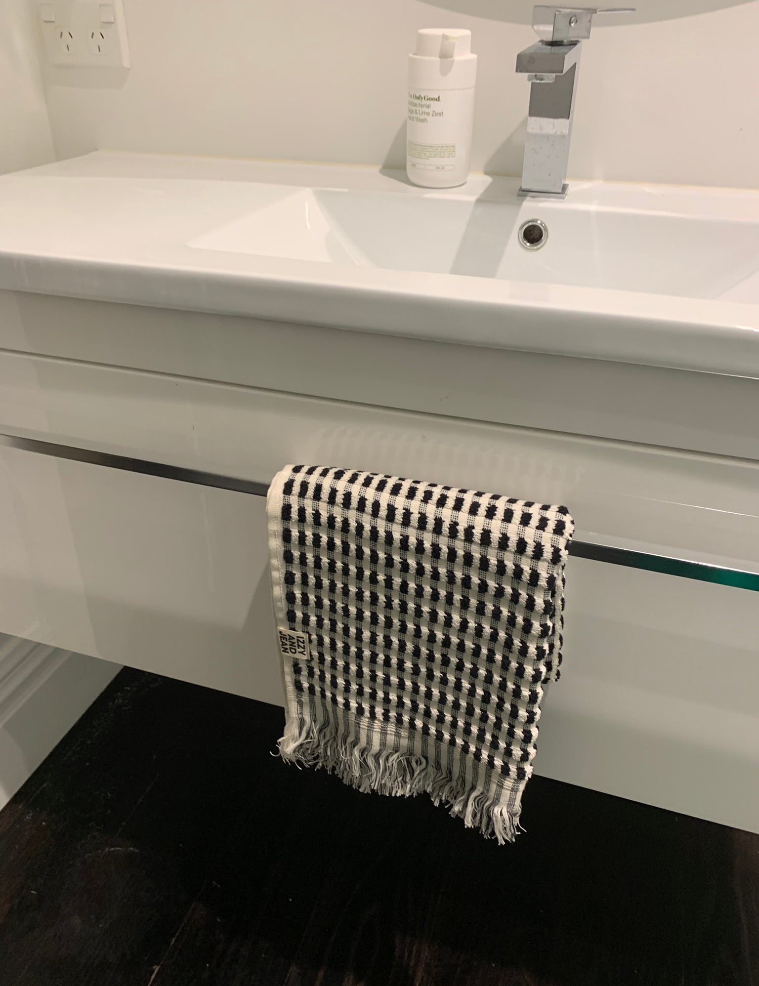A black and white dotted cotton bath towel hanging on a towel rail on a bathroom sink