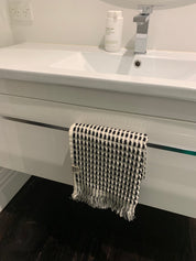 A black and white dotted cotton bath towel hanging on a towel rail on a bathroom sink