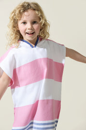 Child wearing a pink and white striped hooded Turkish towel on a plain background