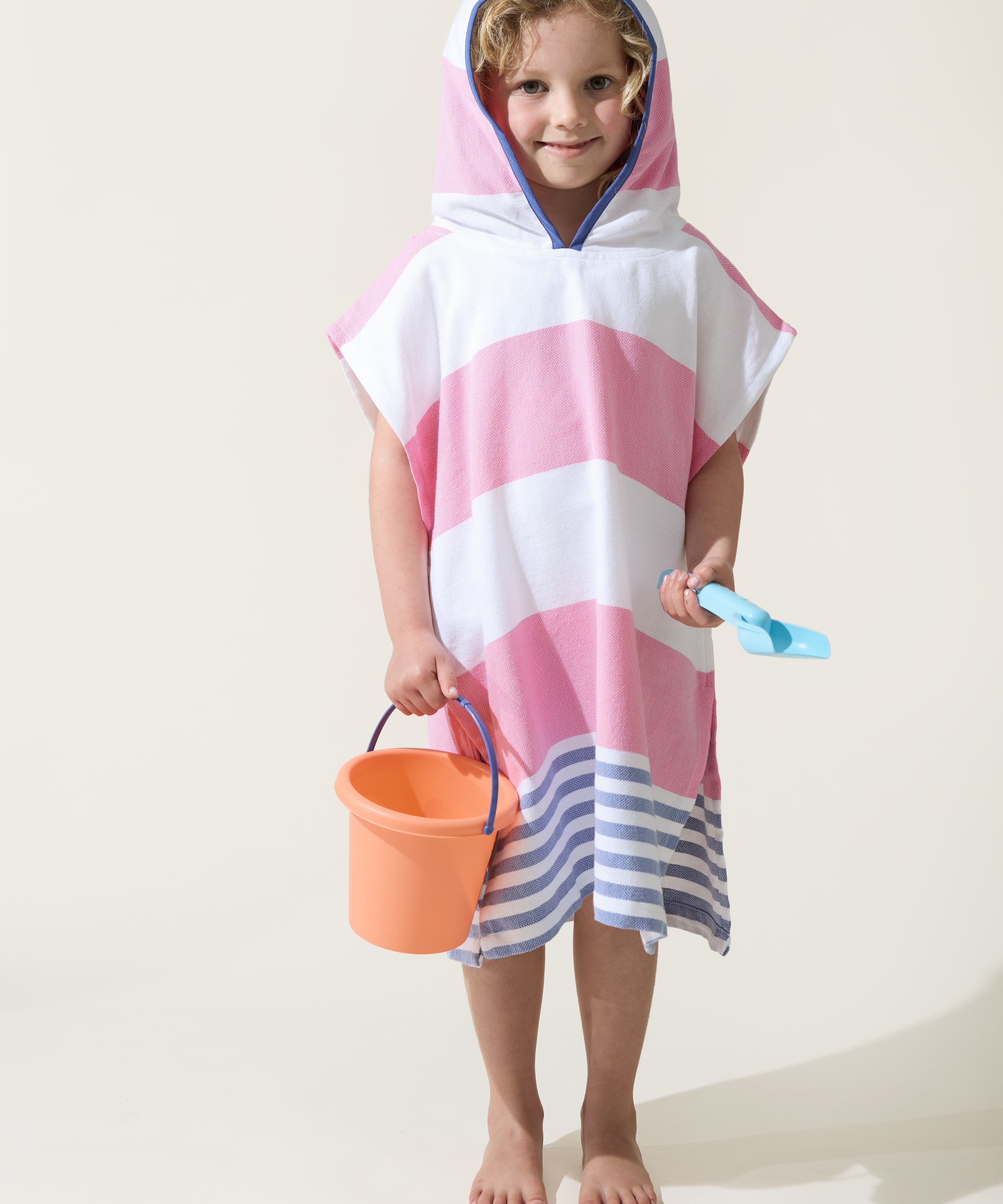 A little girl wearing the Ezy-towelie with the hood on. Stripped Turkish towel with hood in Pink and Blue.
