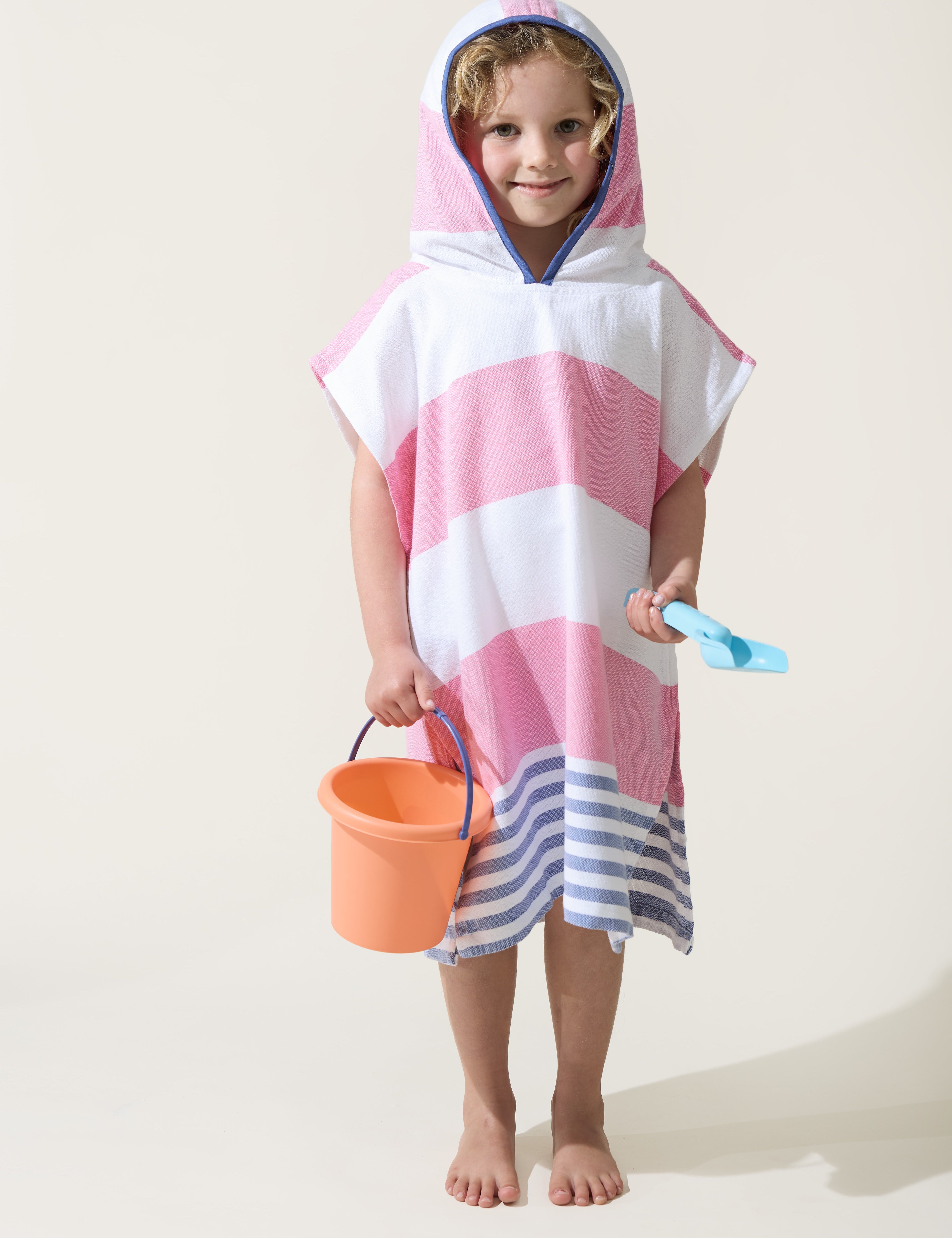 A little girl wearing the Ezy-towelie with the hood on. Stripped Turkish towel with hood in Pink and Blue.