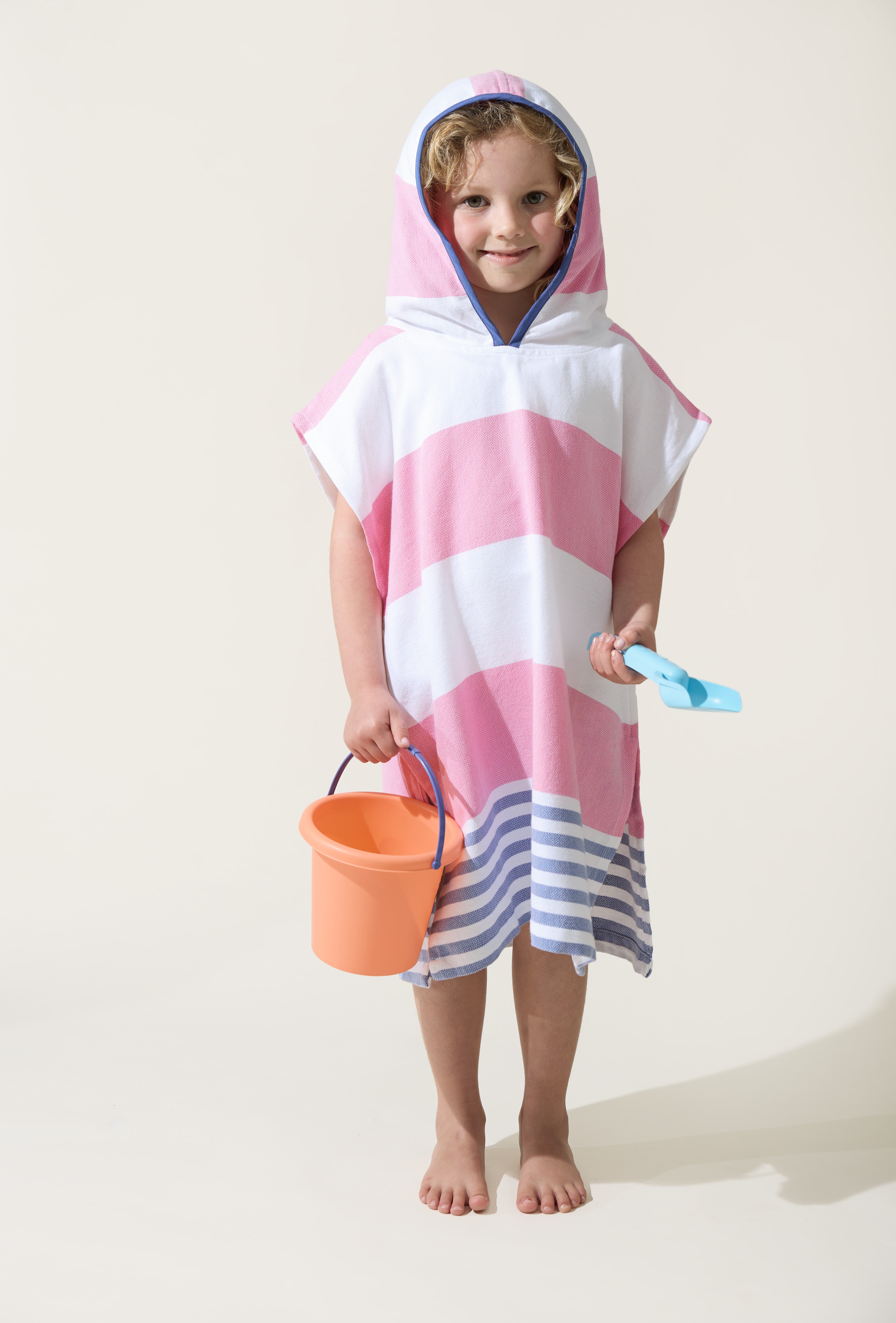A little girl wearing the Ezy-towelie with the hood on. Stripped Turkish towel with hood in Pink and Blue.