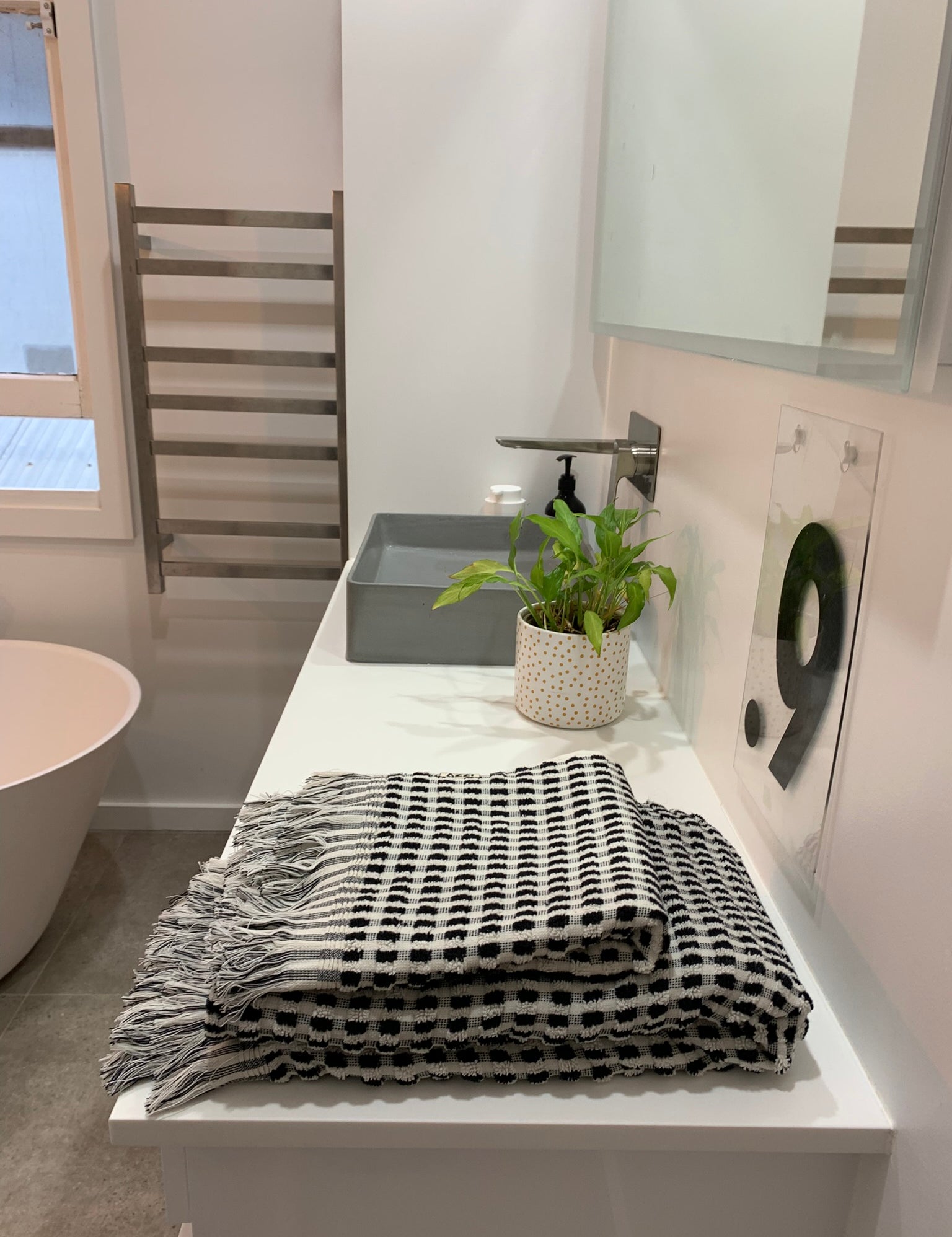 The Amalfi bathroom towel set with sheet and hand towel, in white with black dots in a checkered pattern and tassles.