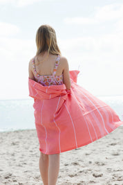  A girl on a beach wrapped in a coral Classic Turkish Towel