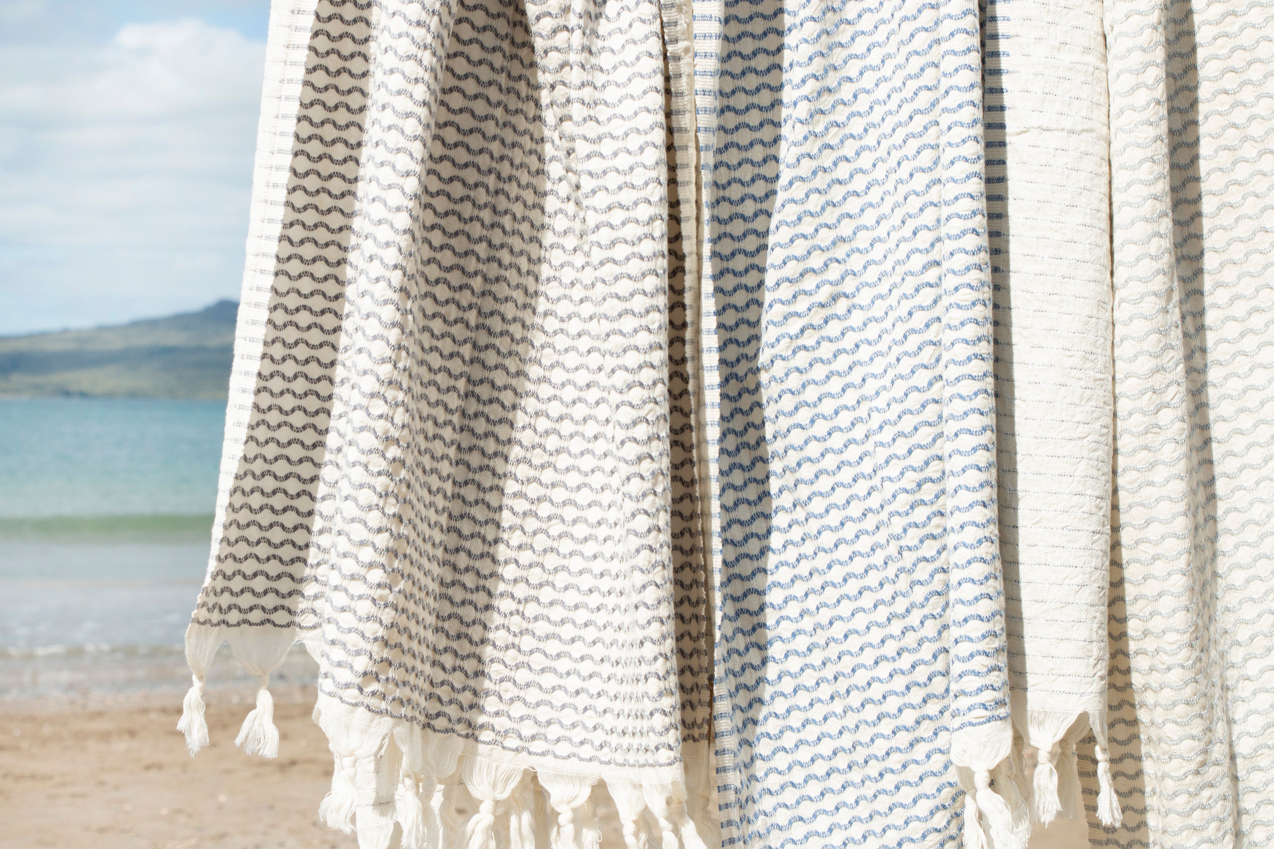 Anatolia Izzy and Jean Turkish Towel, with textured diamond shape and tassels on a beach