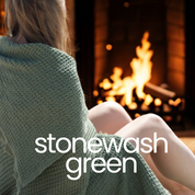 Person wrapped in a green blanket sitting by a fireplace with 'stonewash green' text overlay.