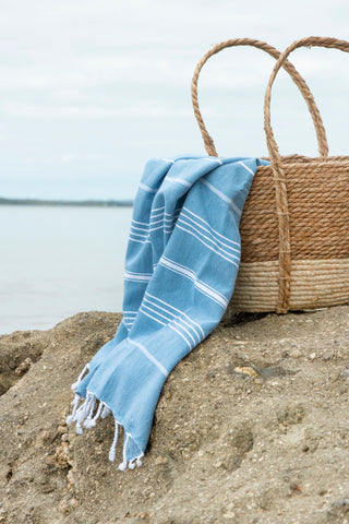 A striped Turkish towel in Aegean Blue with white stripes and fringes on the edges.