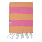 A striped Santorini Turkish towel beach towel with horizontal bands of melon and pink, with white fringes on the edges.
