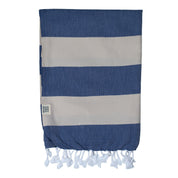 A folded striped Santorini Turkish towel with navy and sand colours, featuring white fringes on the edges.