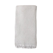 A pale grey coloured waffle bath towel folded on a white background