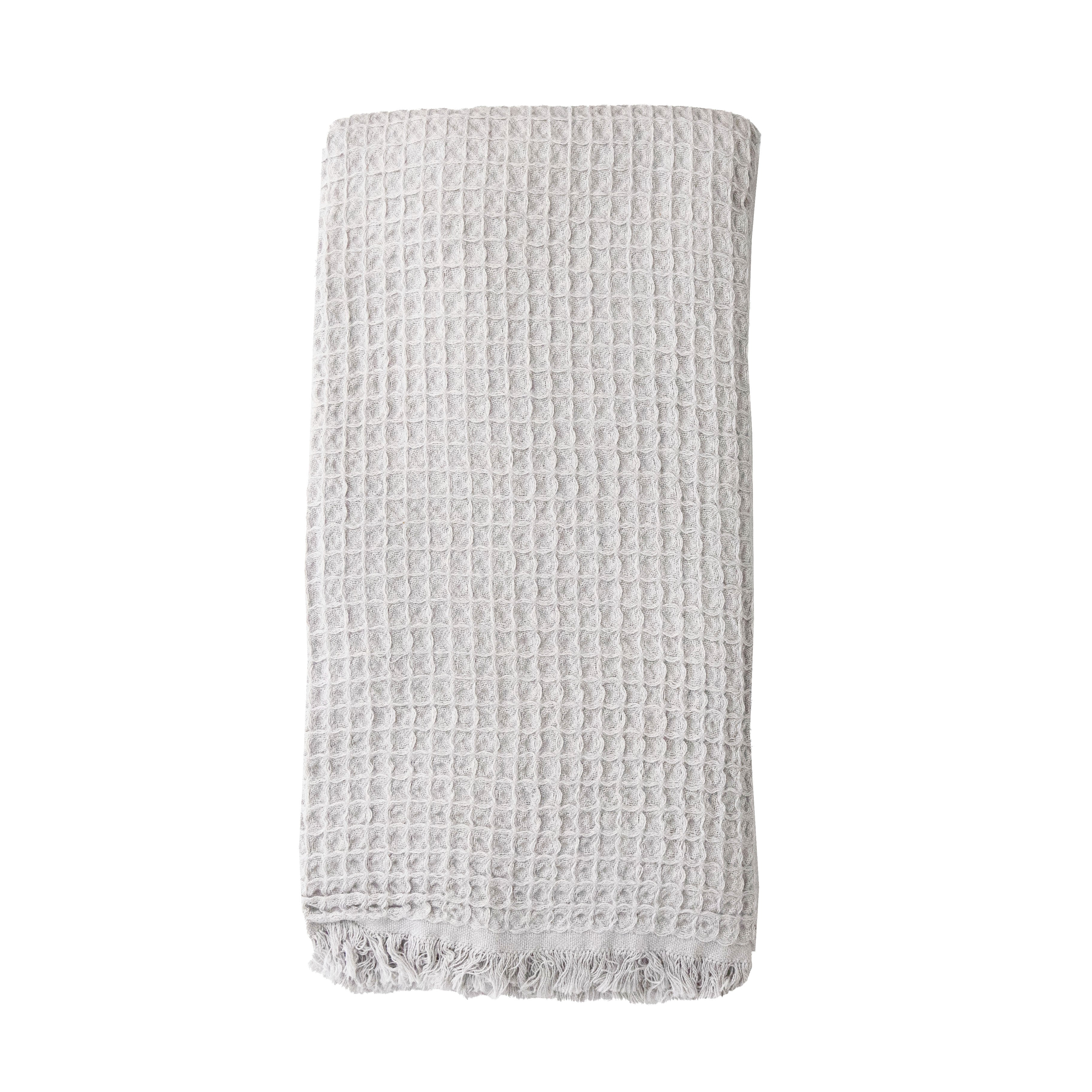 A pale grey coloured waffle bath towel folded on a white background