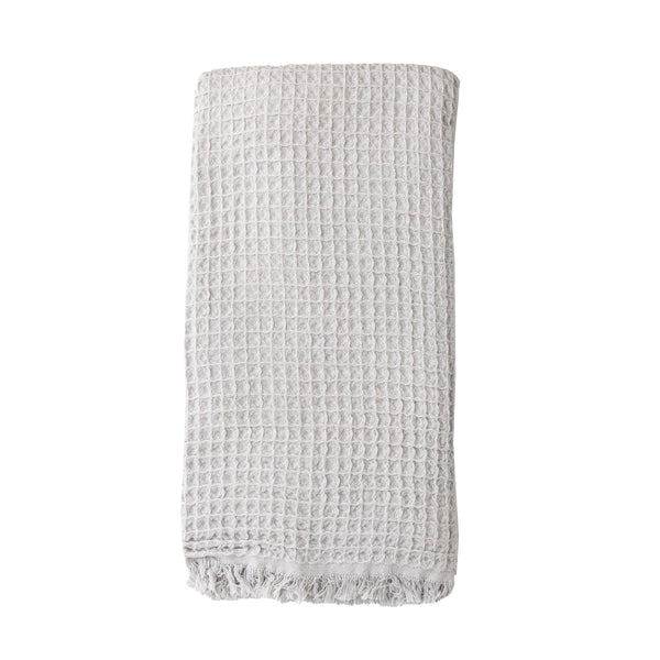 A pale grey coloured waffle bath towel folded on a white background