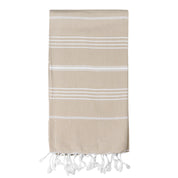 A beige/sand coloured Turkish towel with white stripes and tassels on the bottom edge.