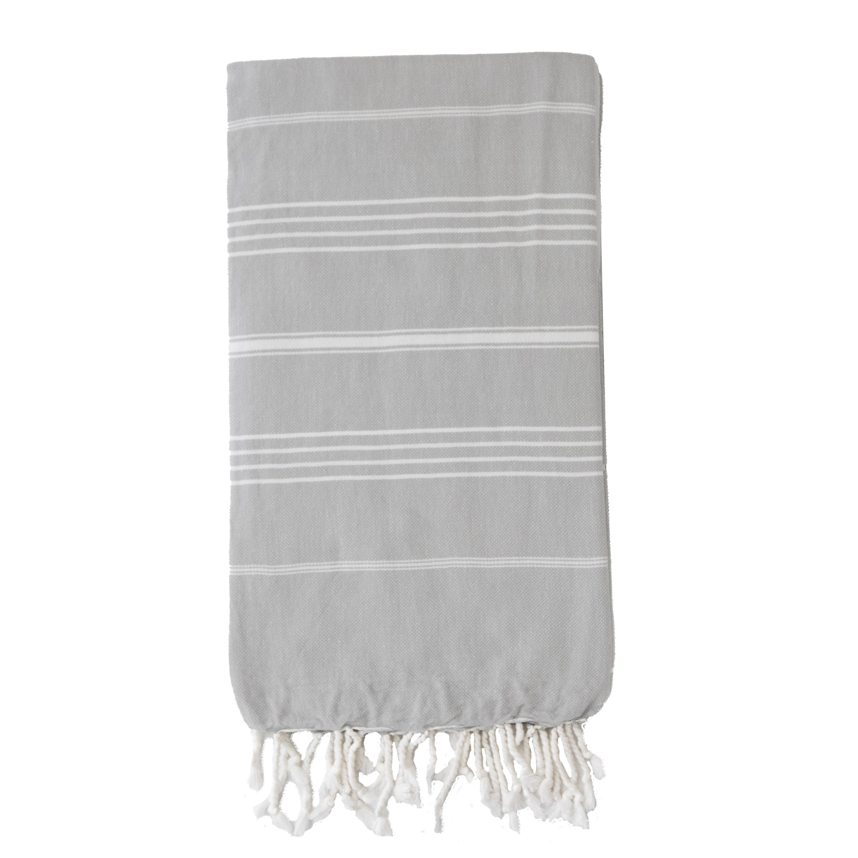 A folded pale grey Turkish towel with white stripes and tassels on the bottom edge.