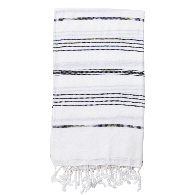 A folded white Turkish towel with black stripes and tassels on the bottom edge.
