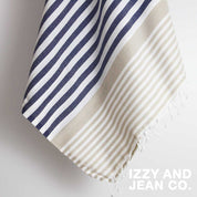 A close up of the Navy and Sand striped Sofia Turkish Towel with tassles at the bottom