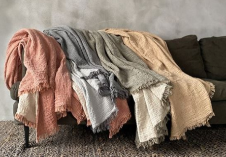 4 colours of the Haven throw blankets in mustard, sage, dark grey and orange, thrown in a display over a couch.