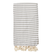 A gray striped St Tropez Turkish towel with white tassels on the ends, displayed on a white background.